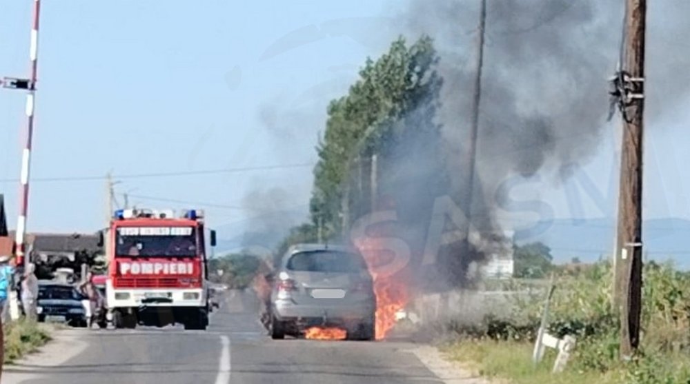 FOTO. Mașină mistuită de flăcări. Nor gros de fum, lângă trecerea la nivel cu calea ferată